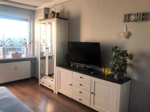 una sala de estar con TV de pantalla plana en un armario blanco en Apartament SŁONECZNY Mrzeżyno en Mrzeżyno