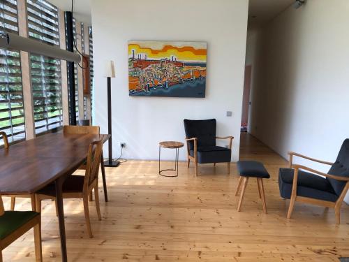 Habitación con mesa, sillas y un cuadro en la pared. en Holiday House Randu Pļavas, en Salacgrīva
