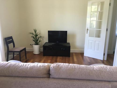 a living room with a couch and a flat screen tv at Summer house with BBQ and Garden in Horta