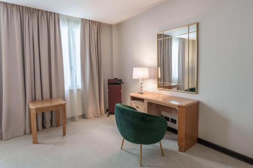 um quarto com uma secretária, um espelho e uma cadeira em Hôtel Le Picardy em Saint-Quentin