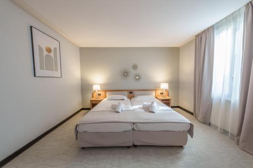 1 dormitorio con 1 cama blanca grande y 2 almohadas en Hôtel Le Picardy, en Saint-Quentin
