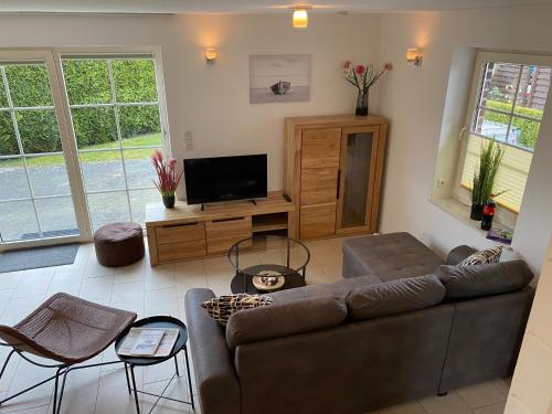 ein Wohnzimmer mit einem Sofa und einem Flachbild-TV in der Unterkunft Neuhaus Deichperle in Krummhörn