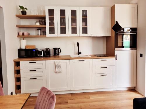 a kitchen with white cabinets and a table and chairs at Supeluse 7-1 Guest Apartment by Annalie Apartments in Pärnu