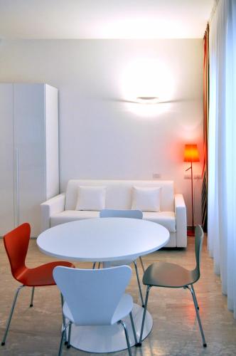 un soggiorno con tavolo e sedie bianchi di BB Hotels Aparthotel Bocconi a Milano