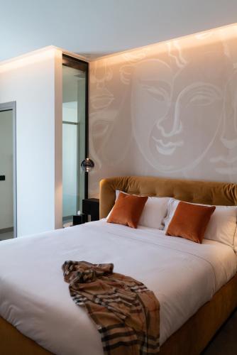 a bedroom with a bed with a painting of a face on the wall at 3T Boutique Hotel in Ivrea