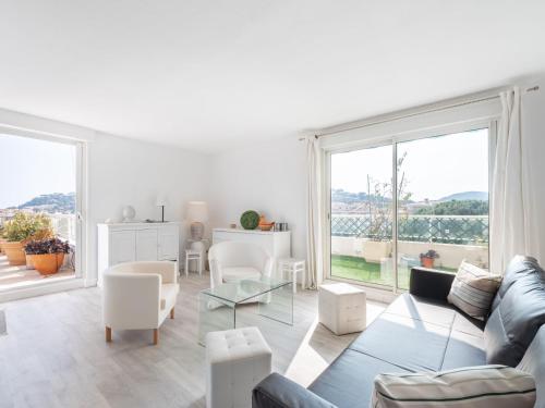 uma sala de estar com mobiliário branco e uma grande janela em Apartment Turquoise-8 by Interhome em Cavalaire-sur-Mer