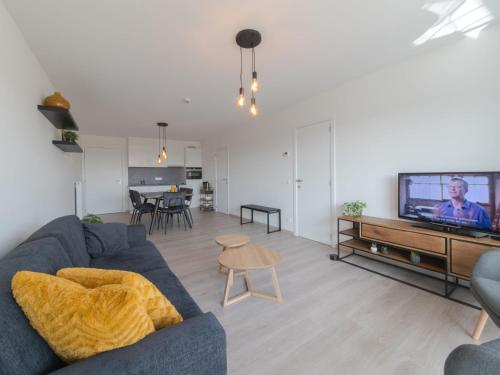 a living room with a blue couch and a tv at Apartment Railway to the Beach with balcony by Interhome in Blankenberge