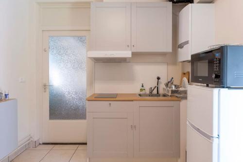 La cuisine blanche est équipée d'un évier et d'un réfrigérateur. dans l'établissement Front room in Villa near Centre and TUe, à Eindhoven