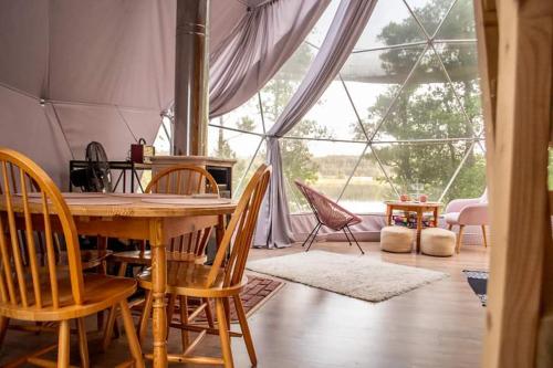a dining room with a table and chairs and a large window at Niezwykła Cisza Glamping & Sauna in Zelwa