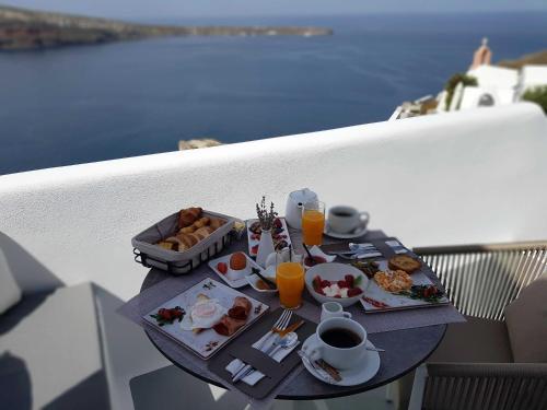 a breakfast table with food and drinks on a balcony at Marizan Caves & Villas in Oia