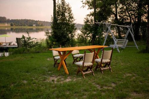 a wooden table with chairs and a swing at Niezwykła Cisza Glamping & Sauna in Zelwa
