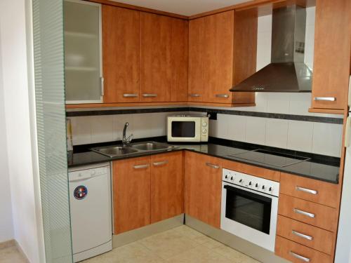 La cuisine est équipée de placards en bois, d'un évier et d'un four micro-ondes. dans l'établissement Apartment Apartamentos Golden Beach by Interhome, à Sant Carles de la Ràpita