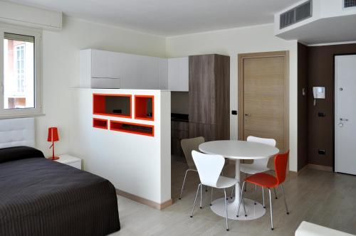 um quarto com uma cama, uma mesa e cadeiras em BB Hotels Aparthotel Bicocca em Milão