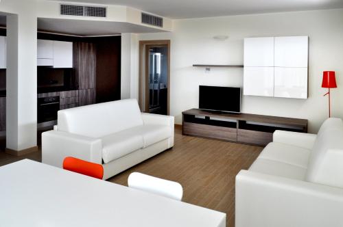 a living room with white furniture and a flat screen tv at BB Hotels Aparthotel Bicocca in Milan