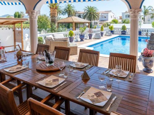 - une table en bois avec des verres à vin sur une terrasse avec une piscine dans l'établissement Holiday Home Romulia by Interhome, à Empuriabrava