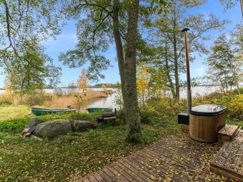 a tree and a trash can next to a lake at Holiday Home Anttoora a-sauna by Interhome in Pori