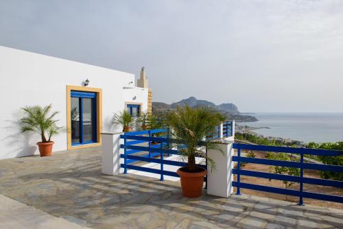 a white house with a blue fence and plants at Villa Leonardo in Archangelos