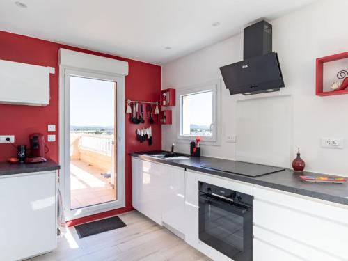 une cuisine avec des placards blancs et un mur rouge dans l'établissement Apartment Les Roches Bleues-1 by Interhome, au Pradet