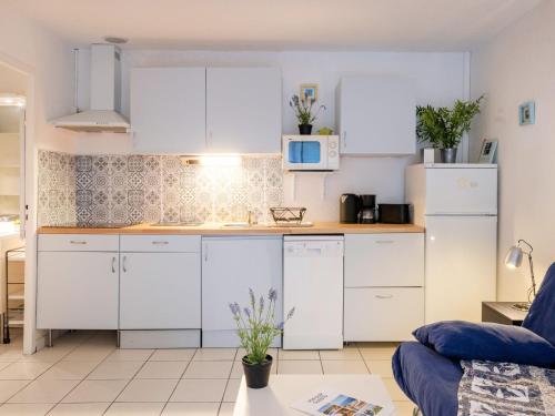 une cuisine avec des armoires blanches et des appareils électroménagers blancs dans l'établissement Holiday Home Les Pins-12 by Interhome, à Lacanau-Océan