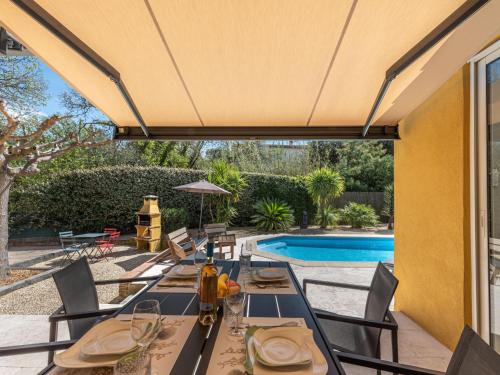 un patio con mesa y sillas junto a una piscina en Holiday Home Le Clos du Mûrier by Interhome en Cogolin