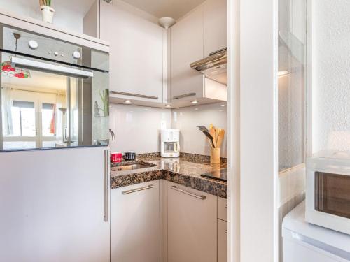 une cuisine avec des armoires blanches et un micro-ondes dans l'établissement Apartment Le Grand Large by Interhome, à Seignosse