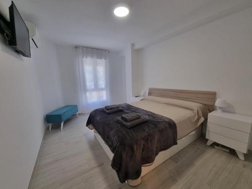 a white bedroom with a bed and a dresser at Apartamentos en Denia frente al Puerto! in Denia