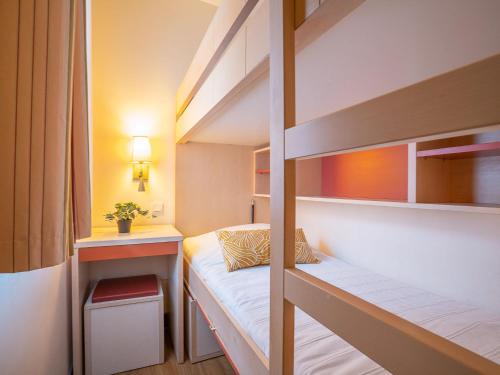 Cette petite chambre comprend des lits superposés et un bureau. dans l'établissement Studio Le Village - C3 217 by Interhome, à Agay