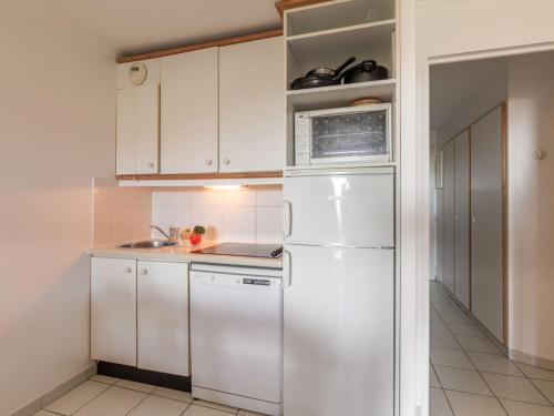 une cuisine avec des armoires blanches et un réfrigérateur blanc dans l'établissement Apartment Le Hameau - K3 122 by Interhome, à Agay