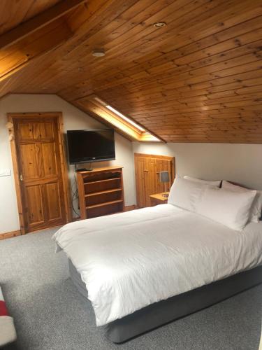 Schlafzimmer mit einem großen weißen Bett und Holzdecken in der Unterkunft Lough Aduff Lodge 5 minutes from Carrick on Shannon in County Leitrim