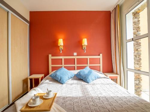 une chambre avec un lit et un mur rouge dans l'établissement Apartment Le Village - C4 008 by Interhome, à Agay