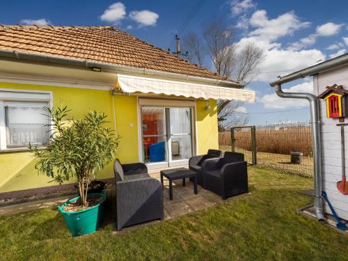 une maison jaune avec des chaises noires et une plante dans l'établissement Holiday Home Lisa by Interhome, à Balatonboglár