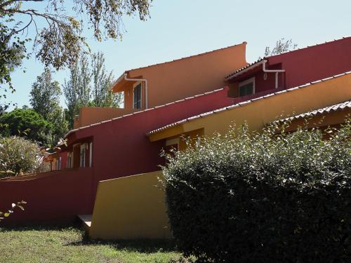 une maison rouge et jaune avec des buissons devant elle dans l'établissement Holiday Home Cala Bianca-1 by Interhome, à Borgo