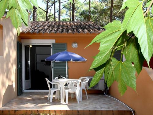 une terrasse avec une table, des chaises et un parasol dans l'établissement Holiday Home Cala Bianca-1 by Interhome, à Borgo
