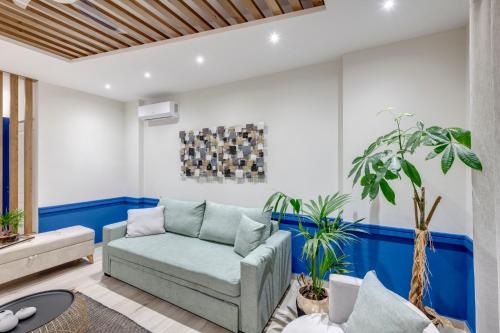 a living room with a blue couch and plants at Polis Suite in Ermoupoli