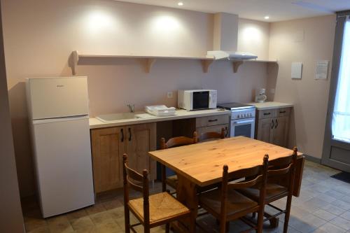a kitchen with a table and a white refrigerator at Domaine de Peyreguilhot in Laparade