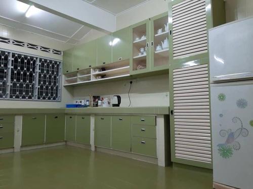 uma cozinha com armários verdes e um frigorífico branco em Simple Home Taiping 简居 Lakeview em Taiping