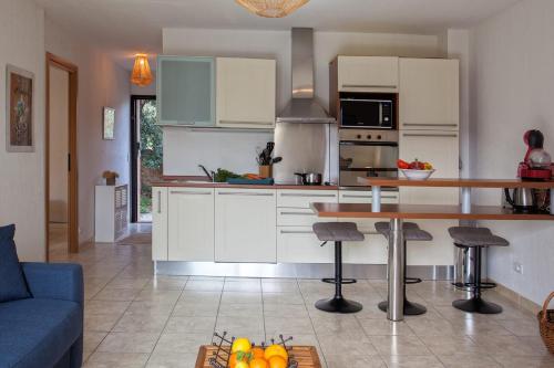 une cuisine avec des placards blancs et une table avec des tabourets de bar dans l'établissement Appartement Casa Linda avec jardin 900m de la plage et du centre ville, à Calvi