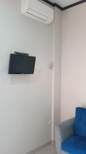a room with a blue chair and a tv on a wall at Mommy Cafe Guesthouse in Pangandaran