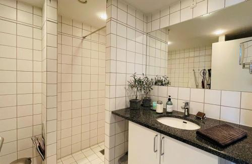 y baño de azulejos blancos con lavabo y ducha. en ApartmentInCopenhagen Apartment 1486, en Copenhague