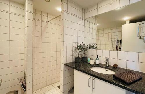 a white tiled bathroom with a sink and a shower at ApartmentInCopenhagen Apartment 1486 in Copenhagen
