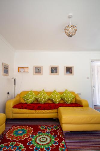 a yellow couch in a living room with a rug at Krissie's in Marazion