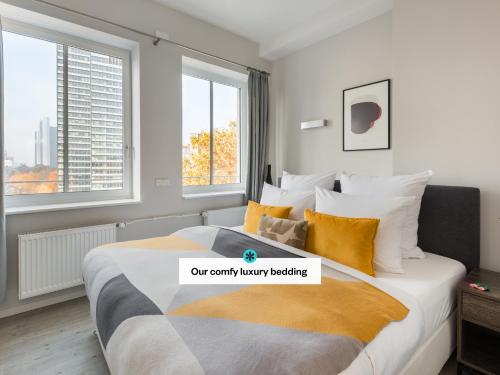 una camera da letto con un grande letto con cuscini gialli e bianchi di numa I Blau Apartments a Francoforte sul Meno