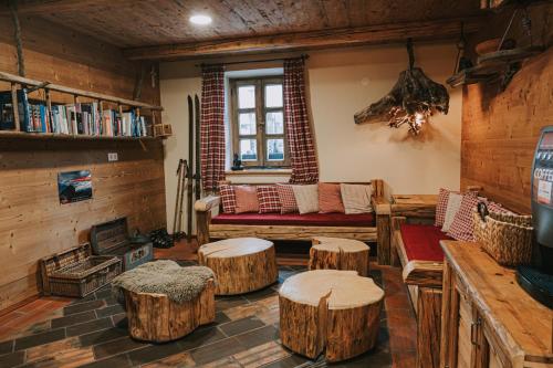 a living room with logs and a couch and tables at Hostel Lukna in Mojstrana