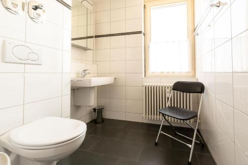 La salle de bains est pourvue de toilettes, d'un lavabo et d'une chaise. dans l'établissement Ferienwohnpark Immenstaad am Bodensee Zwei-Zimmer-Apartment 51 13, à Immenstaad am Bodensee