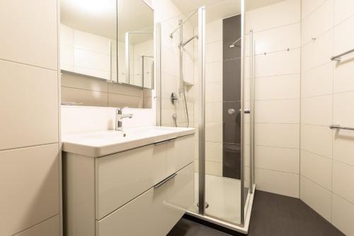 La salle de bains blanche est pourvue d'un lavabo et d'une douche. dans l'établissement Ferienwohnpark Immenstaad am Bodensee Zwei-Zimmer-Apartment 55 29, à Immenstaad am Bodensee