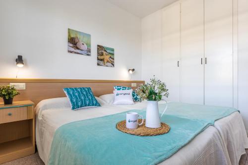a bedroom with a bed with two mugs and flowers on it at Apartamentos Riviera Arysal in Salou