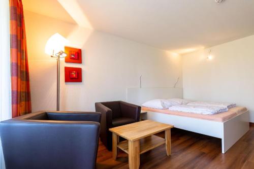 Zimmer mit einem Bett, einem Stuhl und einem Tisch in der Unterkunft Ferienwohnpark Immenstaad am Bodensee Ein-Zimmer-Apartment 49 17 in Immenstaad am Bodensee
