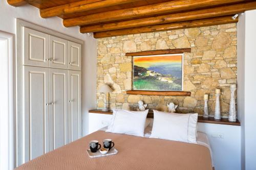 a bedroom with a bed with a stone wall at Aria Boutique Hotel in Chora Folegandros
