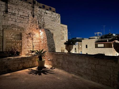 una pared de piedra con una maceta delante de un edificio en Palazzo Morola XIV century, en Giovinazzo