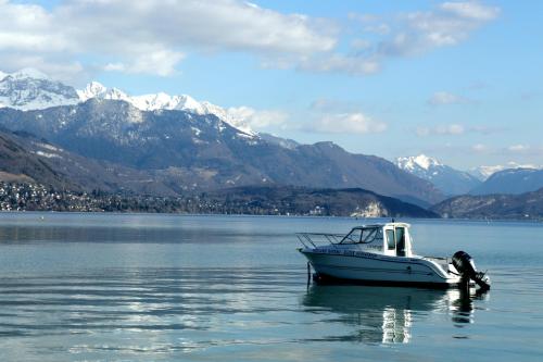 un bateau dans l'eau avec des montagnes en arrière-plan dans l'établissement Coeur d'Annecy, Idéalement situé, à Annecy